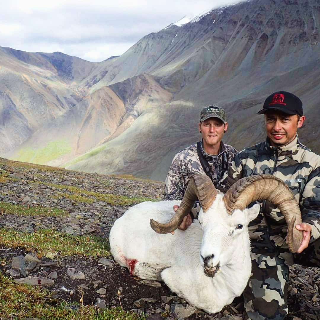 two hunters with hunted ram in the field