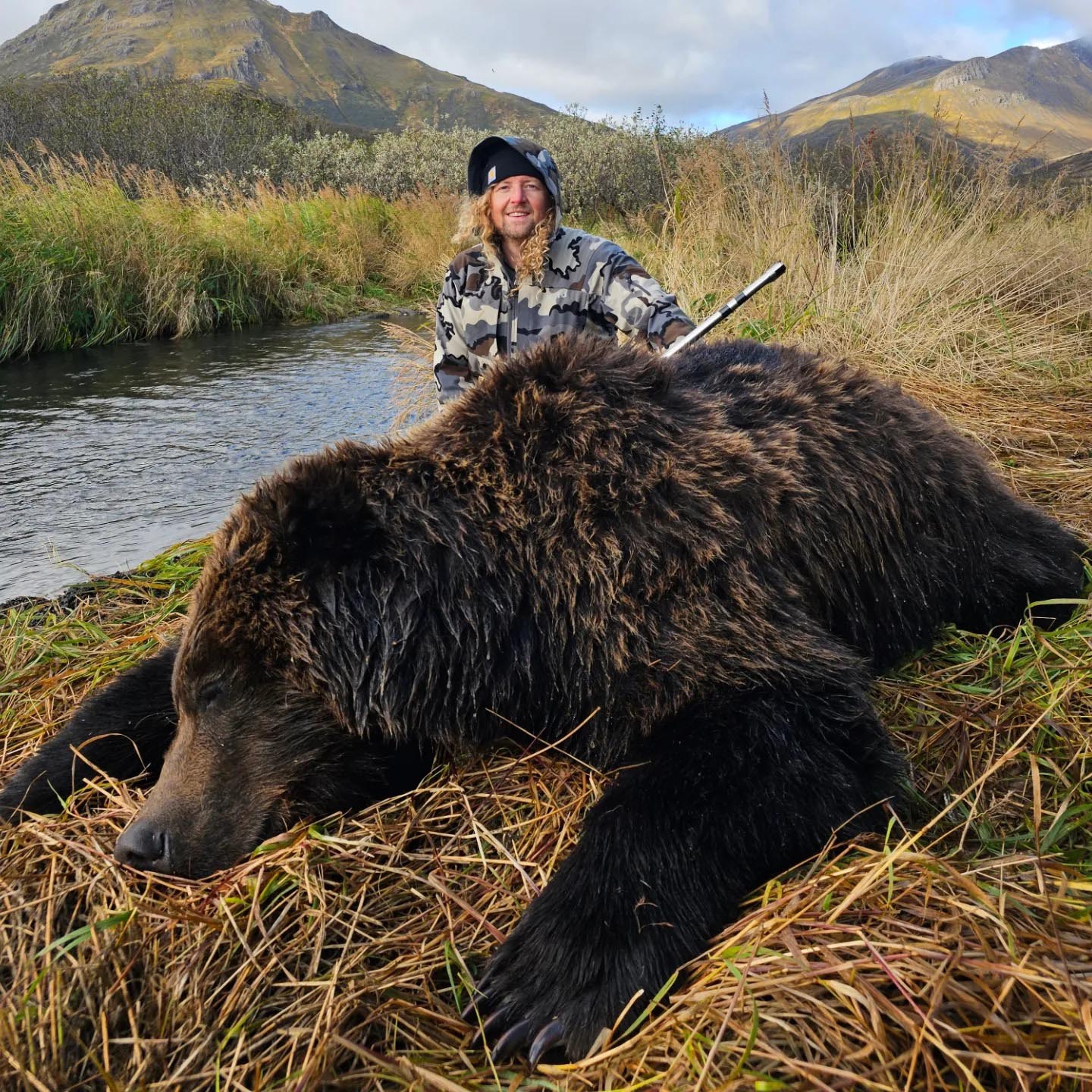 hunter holding rifle with large brown bear